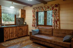 a living room with a couch and a kitchen at Podlaska Chatka Dziadka in Ciwoniuki