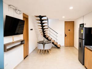 a living room with a tv and a spiral staircase at Laureles Premium Loft con Jacuzzi Privado in Medellín