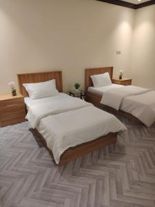 two beds in a room with white sheets at Sukoon Apartment شقة سكون 2 in Buraydah