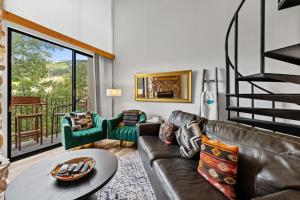 a living room with a leather couch and a staircase at Summit House East #313 in Copper Mountain