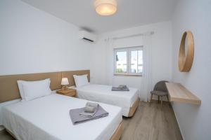 a room with two beds and a table and a chair at Renovated Algarve Apartments with Pool in Armação de Pêra +112 photos