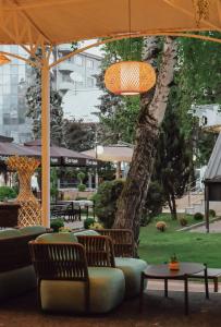 a patio with chairs and tables and a tree at Hotel Rozaje in Rožaje
