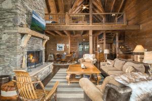 a living room with a stone fireplace in a log cabin at Cucumber Tree Lodge in Banner Elk
