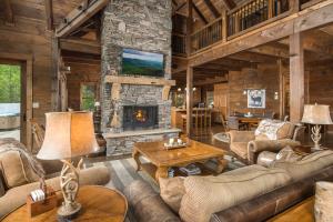 a living room with a stone fireplace in a log cabin at Cucumber Tree Lodge in Banner Elk +41 photos