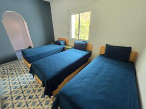 three beds in a room with a window at lagoon apartment 2 in Moulay Bousselham