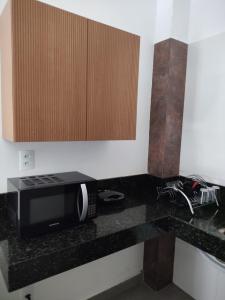 a kitchen with a counter top with a microwave at Lar Doce Lar Realizando Sono suíte1 in Arcos