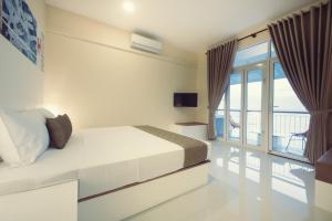 a white bedroom with a bed and a balcony at Hush Lagoon 30 in Negombo
