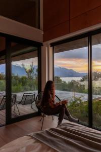 a woman sitting in a chair in front of a window at On The Edge, Luxury - KK43111 in Kaikoura