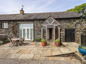 a stone cottage with a patio and a table at Pheasant Cottage in Grange Over Sands