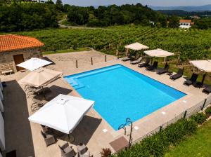 an outdoor swimming pool with umbrellas and chairs at Quinta de Real in Valença