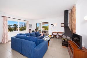 a living room with a blue couch and a tv at Villa Luisa in Cala Galdana