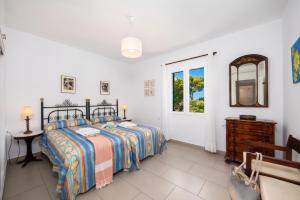 a bedroom with a bed and a table and a window at Villa Luisa in Cala Galdana +17 photos