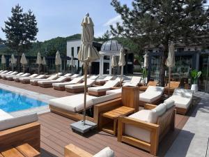 a row of lounge chairs and umbrellas next to a pool at Verde by Hotel Gabriela in Vişeu de Sus