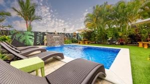 a swimming pool with lawn chairs and a swimming pool at Hormiga's Houses La Fortuna in Fortuna