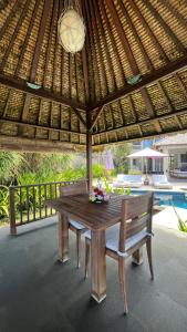 a wooden table and bench under a wooden umbrella at Anapuri Villas in Ketewel