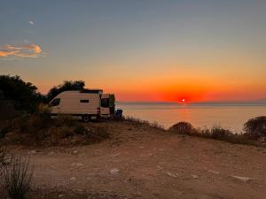a camper parked on the beach with the sunset at Sprinter Camper Albania Rental in Tirana