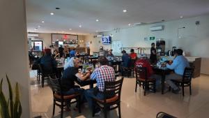a group of people sitting at tables in a restaurant at Hotel Maioris El Diez Culiacan in Culiacán
