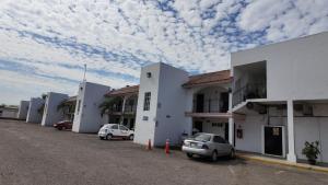 a row of buildings with cars parked in a parking lot at Hotel Maioris El Diez Culiacan in Culiacán