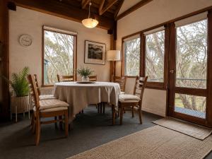 a dining room with a table and chairs and windows at Snow Gums Apartment 16 in Dinner Plain