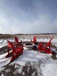 a group of red chairs and a fire pit in the snow at The Lantern Hill Lookout in North Rustico