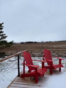 two red chairs sitting on a wooden deck in the snow at The Lantern Hill Lookout in North Rustico