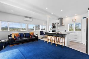 a living room with a black couch and a kitchen at Coromandel Town Harbourside Cottage Luxury Accommodation in Coromandel Town