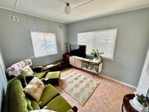 a living room with a green couch and a tv at River Cottage on Cherry - Pet Friendly in Evans Head