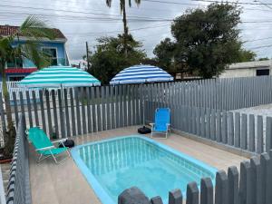two umbrellas and two chairs and a swimming pool at Pousada Siri do Mar in Pontal do Paraná