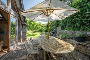 a wooden table with an umbrella on a patio at Airy Barn Conversion Private Parking & Garden in Burrington