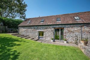 a stone house with a grass yard in front of it at Airy Barn Conversion Private Parking & Garden in Burrington