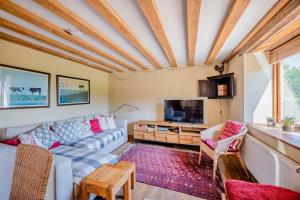 a living room with a couch and a tv at Cosy Barn Conversion with Patio & Private Parking in Burrington
