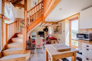 a kitchen and living room with a wooden staircase at Cosy Barn Conversion with Patio & Private Parking in Burrington