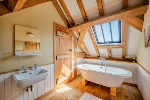a bathroom with a white tub and a sink at Cosy Barn Conversion with Patio & Private Parking in Burrington +8 photos
