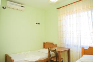 a bedroom with two beds and a table and a window at Hotel Xhejsoni in Shëngjin