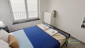 a bedroom with a bed with towels on it at Apartamento acolhedor com AC no centro de Angra in Angra do Heroísmo