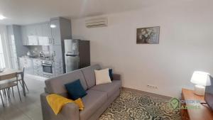 a living room with a couch and a kitchen at Apartamento acolhedor com AC no centro de Angra in Angra do Heroísmo