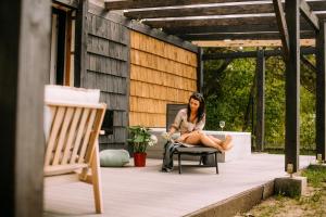 a woman sitting on a chair on a patio at Nomad Cabin Roztocze in Tereszpol Zaorenda
