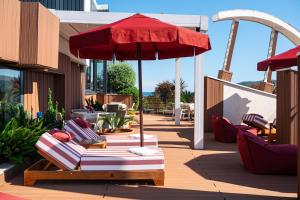 a patio with a red umbrella and lounge chairs at Hotel Imperial Conference & Spa in Budva +100 photos