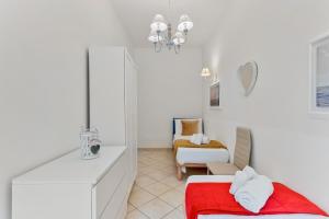 a white room with a red bed and a chair at GOLDEN LUXE - Sunset by the Sea in Lido di Camaiore