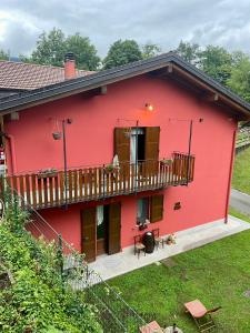 a red house with a balcony and a yard at Casa Iris in Omegna