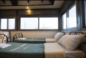 ein Zimmer mit zwei Betten, einer Couch und Fenstern in der Unterkunft Student House in Madaba