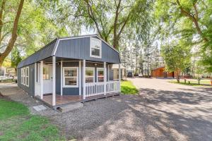 a tiny house with a black roof and a porch at Gateway to Glacier! 2-Cabin Compound for Groups in Columbia Falls