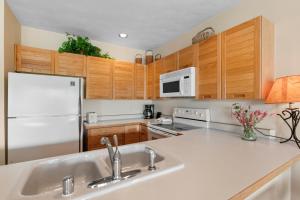 a kitchen with a white refrigerator and wooden cabinets at East Bay Condos #111 in Dillon +26 photos