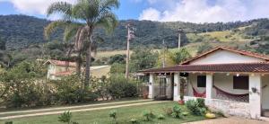 a house with a palm tree in the foreground at Chácara Rancho Imperial - Socorro - SP - Piscina, Churrasqueira, Forno à Lenha, Campo de Futebol e uma linda Vista para a Montanha! in Socorro