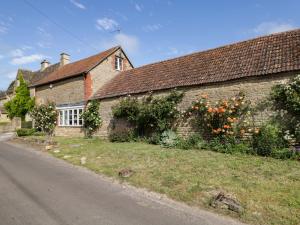 an old brick house with flowers on the side of the road at Granary Cottage in Chippenham