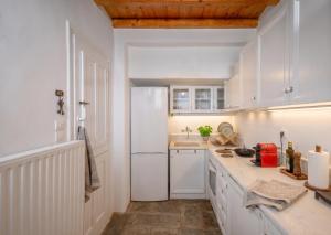 a kitchen with white cabinets and a white refrigerator at Oneiro Serifos House in Serifos Chora +8 photos