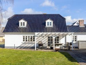 a white house with a black roof and a table at 5 person holiday home in Øster Assels-By Traum in Øster Assels