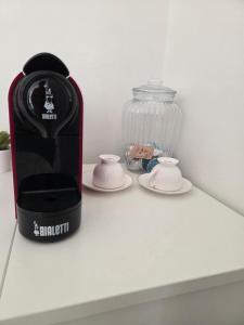 a coffee maker and cups on a white shelf at Cosy Corner in Tollo