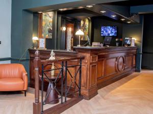 a bar with a desk and a television in a room at Mercure Thurrock Stifford Hall in Grays Thurrock