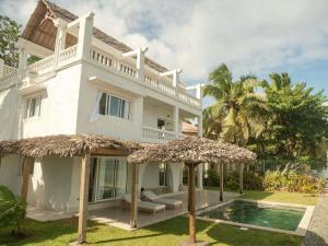 a white house with a swimming pool and an umbrella at Mantis Soanambo Hotel And Spa in Ambondrona